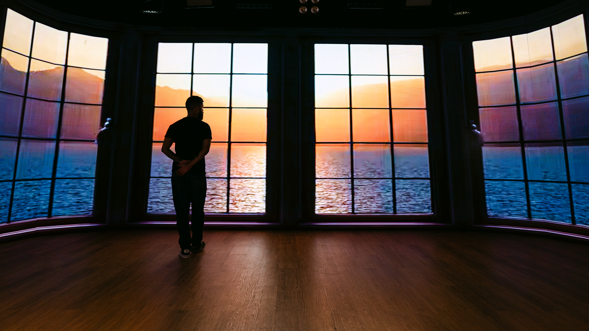 Painel de LED no estúdio exibindo uma paisagem de pôr do sol, com uma pessoa diante da tela